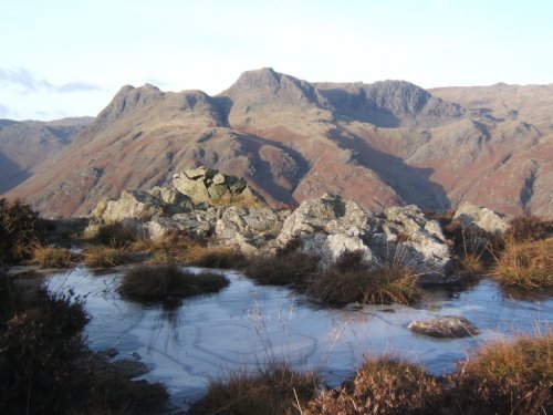 Langdale Pikes with frozen pool on Lingmoor Fell in the foreground.