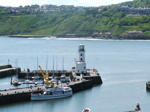 Scarborough, North Yorkshire. View over the harbour with lighthouse and the Coronia tour boat.