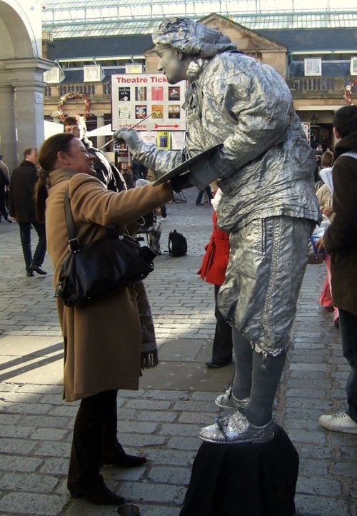 Living Statue giving a freshen up of cosmetics to passing Lady at Covent Garden, Greater London.