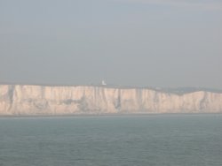 Misty View of the white cliffs of Dover with
the Lighthouse in the background Wallpaper