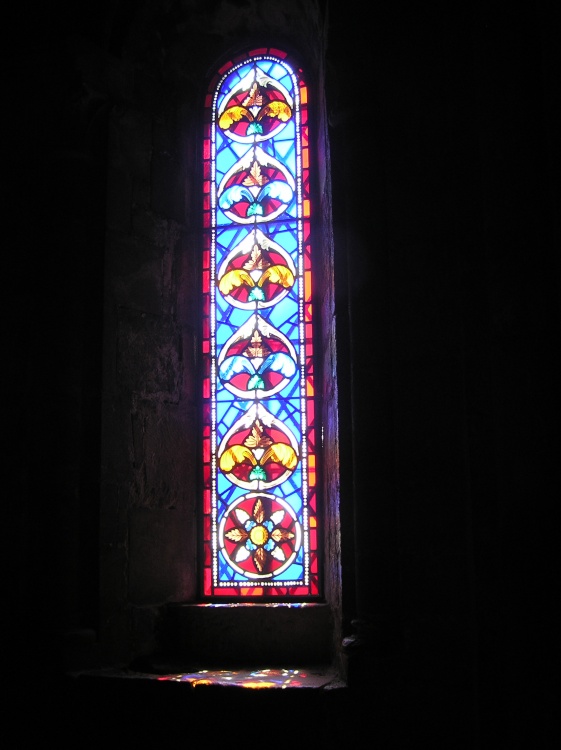 Coloured light shines through a stained glass window and on to the sill at Dover Castle