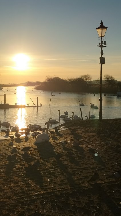 Sunrise over Christchurch harbour from the quay with lamp